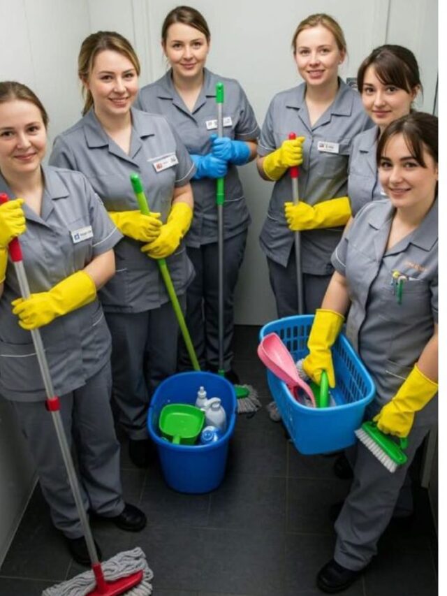 Group of six airline cleaning crew members in gray uniforms and yellow gloves holding cleaning supplies, mops, and buckets, ready for aircraft cleaning.